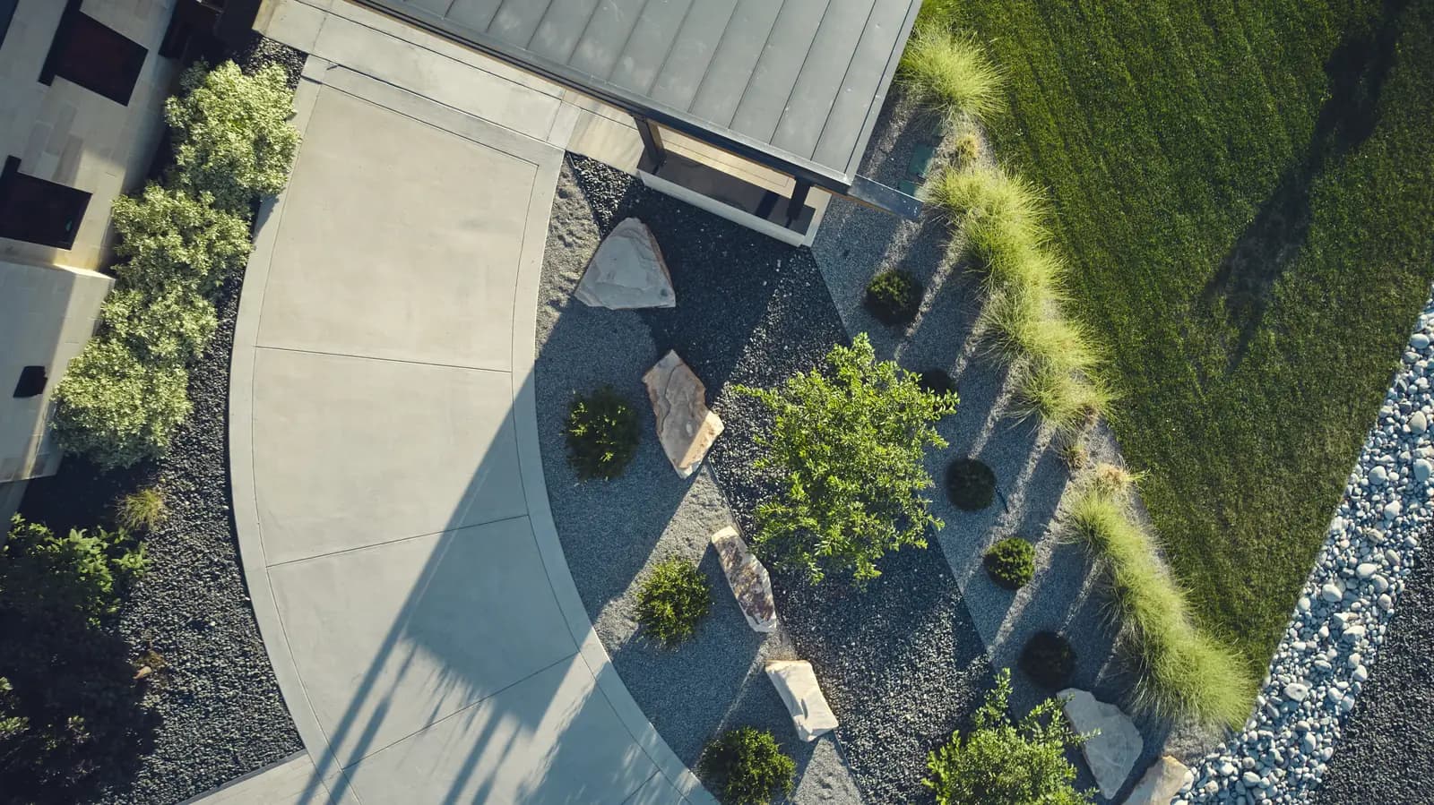 Aerial view of a concrete motor court bordered by ornamental grasses and steel-edged rock beds