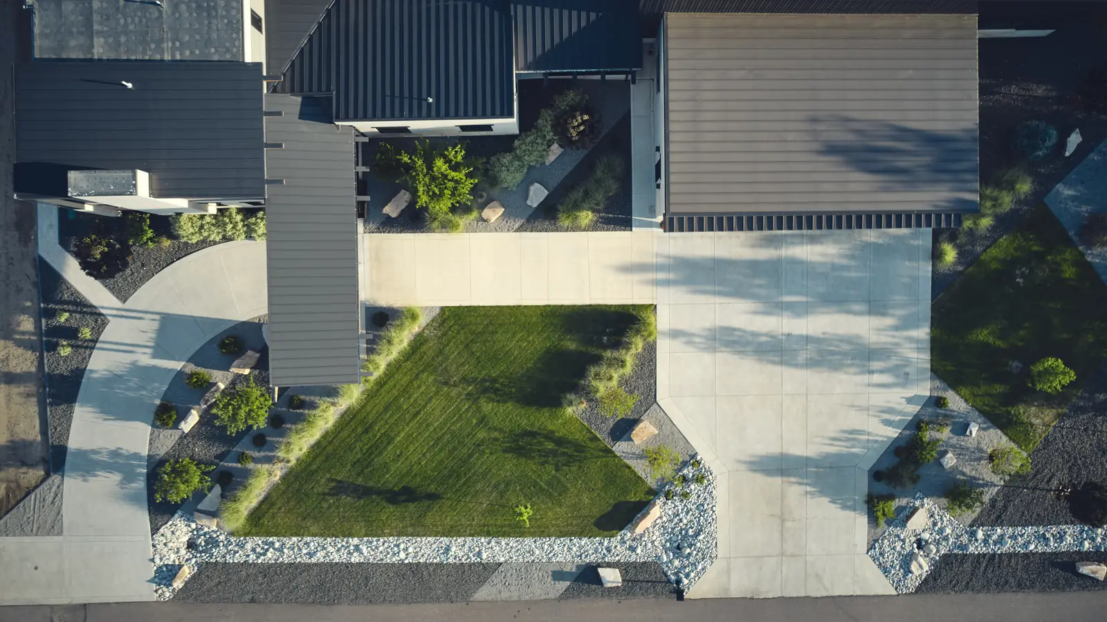 Aerial view of a modern home, hangar, lawn panels, and driveway on a Colorado airpark lot