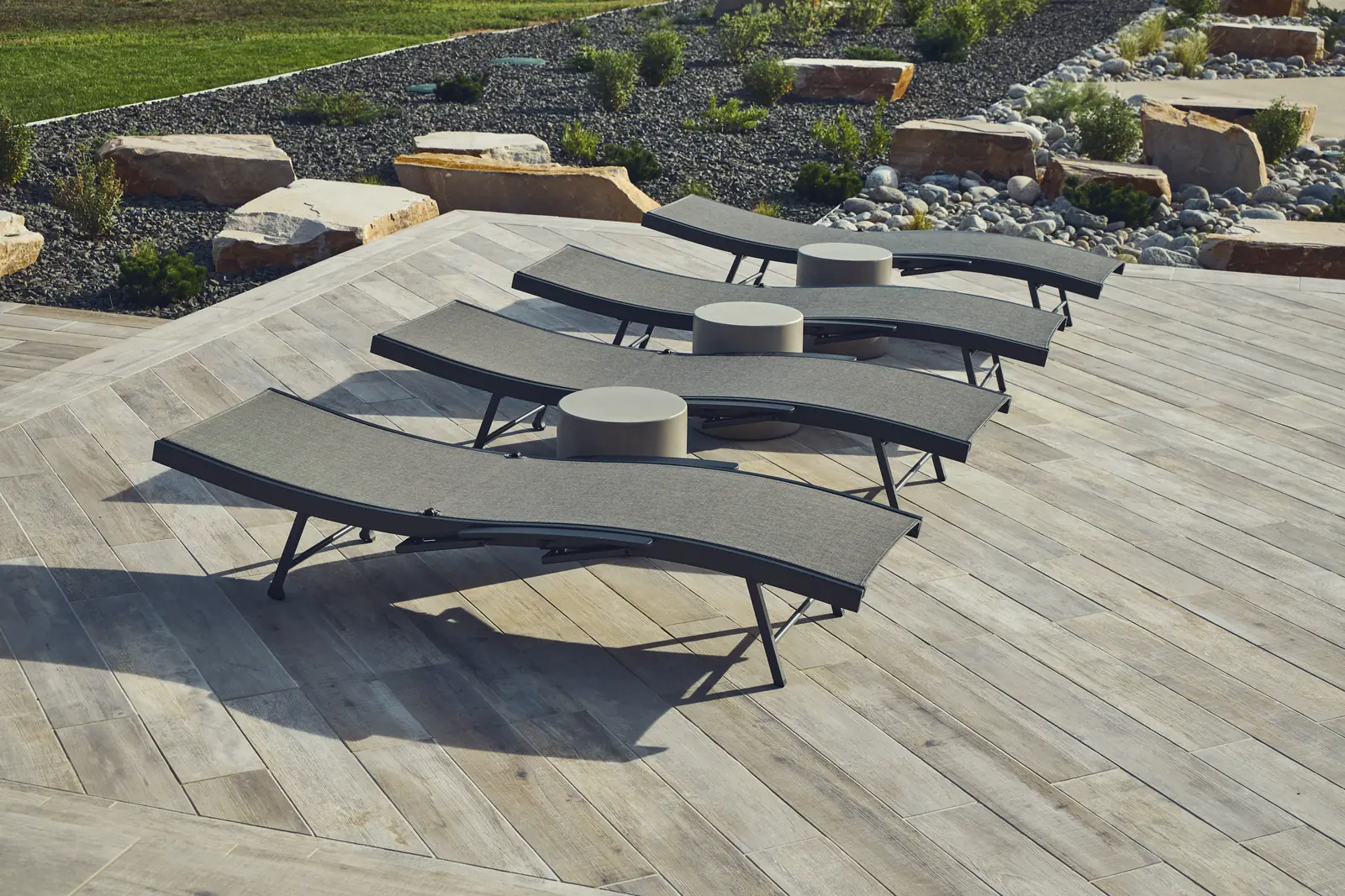 Row of chaise lounges on a wood-look porcelain paver pool deck