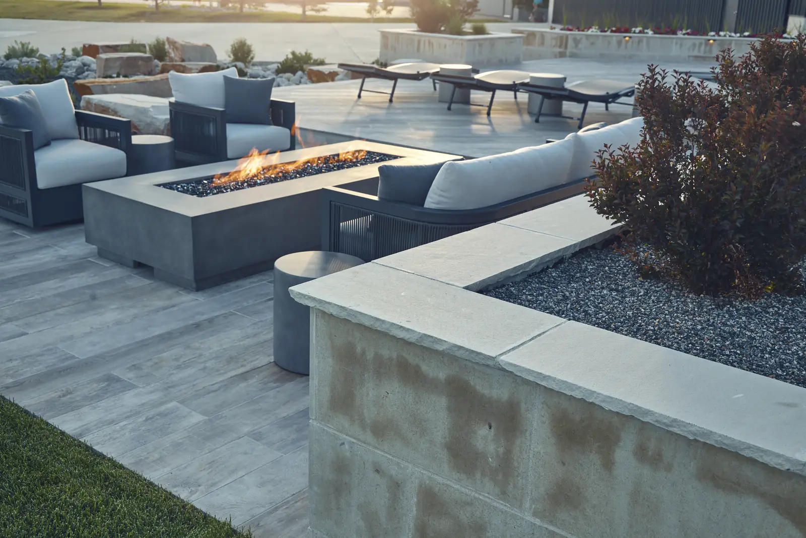 Fire pit lounge with outdoor sofas, concrete fire table, and limestone seat wall