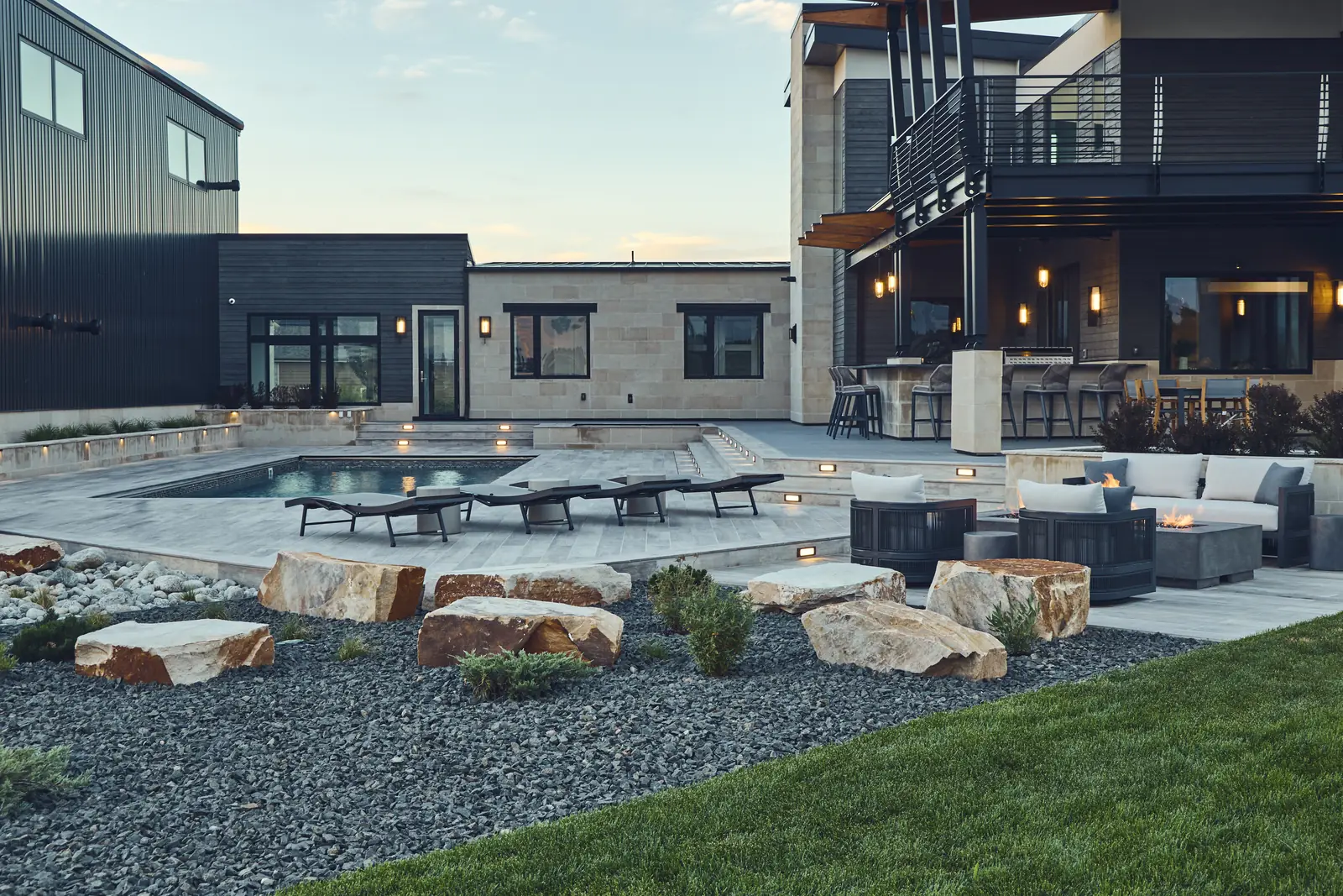 Evening patio with boulders, gravel beds, and the sunken fire pit lounge