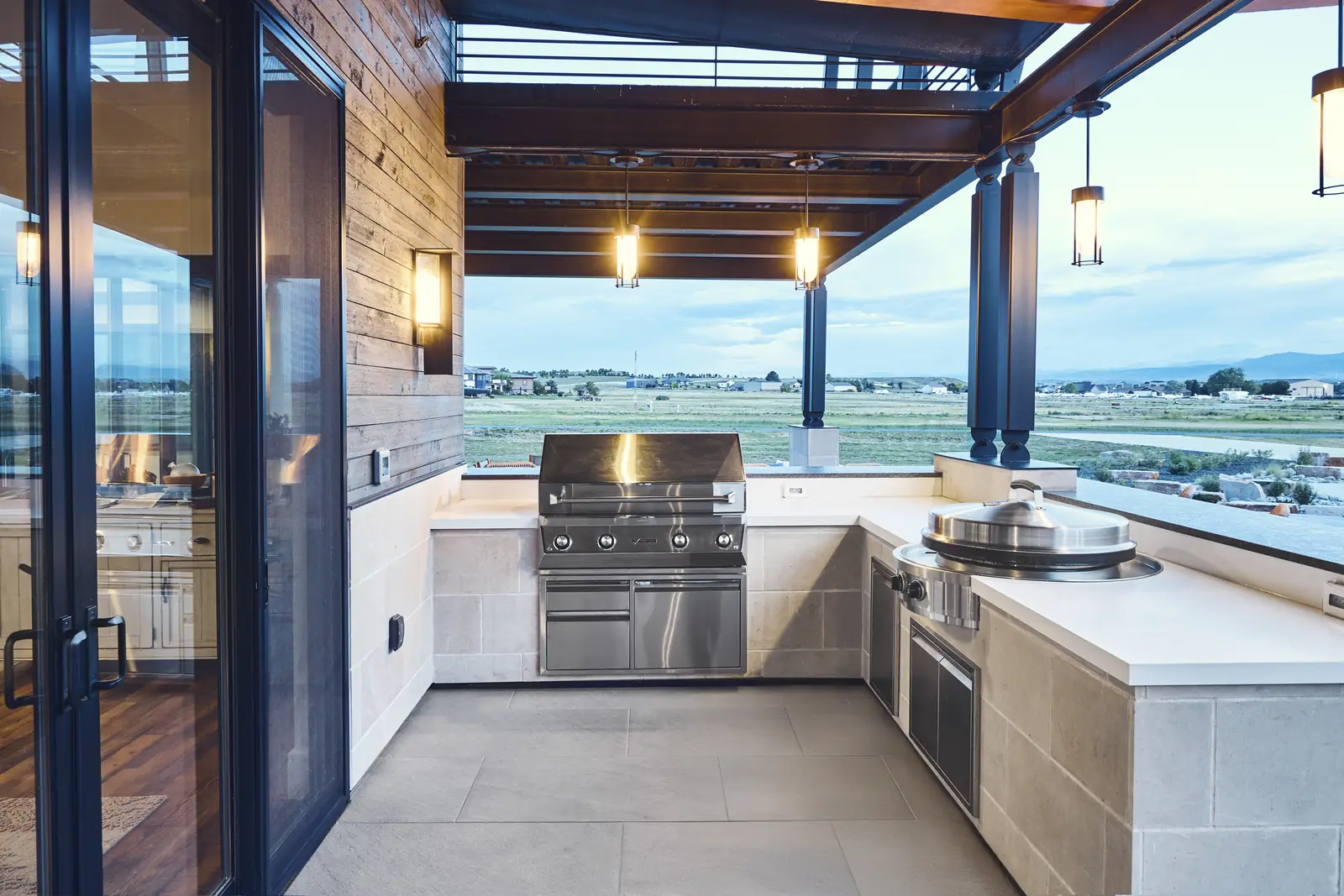 Built-in stainless grill and outdoor kitchen counters under the pergola with prairie views